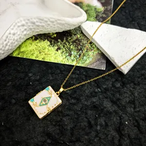 Golden chain necklace with white enamel book pendant, featuring turquoise details and crystal.