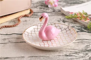 Closeup shot of a cute pink ceramic flamingo jewelry tray with elegant gold trim and pattern.