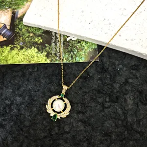Detail view of the gold-tone titanium steel necklace with pearl and green zircon pendant.