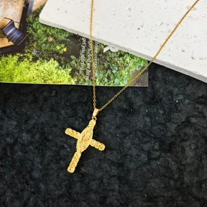Detailed shot of a delicate gold cross pendant necklace featuring intricate religious relief design.