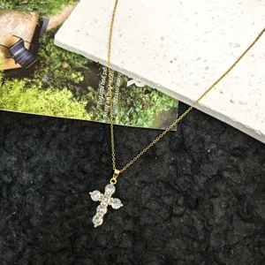Detailed shot of a delicate gold-toned chain necklace featuring a sparkling crystal cross pendant.