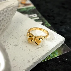 Vue détaillée d'une bague nœud dorée, surface polie et design ouvert réglable élégant.