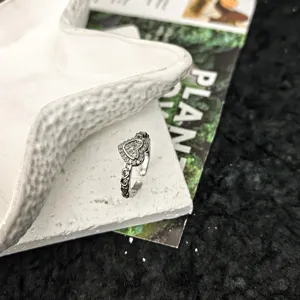 Gros plan du detail d une bague ouverte en argent avec design de coeur et style vintage.