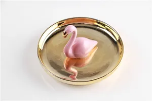 Detail view of the ceramic flamingo jewelry tray showing the shiny gold rim and pink figurine.