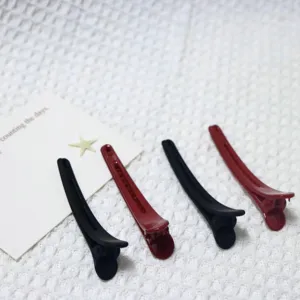 Matte duckbill hair clips close-up, minimalist black and red hair pins for daily wear.
