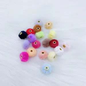 Close-up detail of colorful faux fur pom pom spacer beads with metal holes for DIY jewelry making.