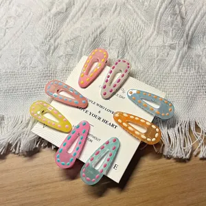 Close-up of colorful resin hair clips with dot patterns displayed on white card detail view.