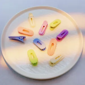 Close-up of colorful candy-colored wavy hair clips arranged neatly on a white ceramic plate.