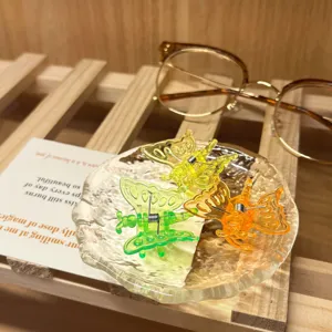 Detailed view of colorful transparent butterfly clips displayed in a glass dish.