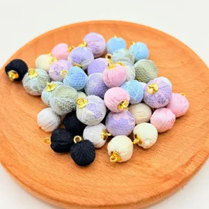 Colorful lace wrapped ball charms with gold loops for DIY jewelry making and craft decor.