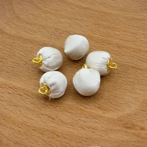 Close-up detail of white fabric wrapped spherical buttons with gold metal loop bases.