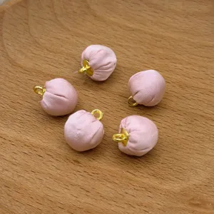 Close-up of pink fabric covered round beads with gold loops for DIY jewelry crafts.