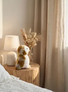 Detailed view of a cute stuffed barn owl plush toy resting on a rustic wooden stool decor.
