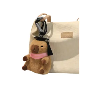 Grazioso ciondolo in peluche di capibara con berretto di laurea e sciarpa rosa per borsa.