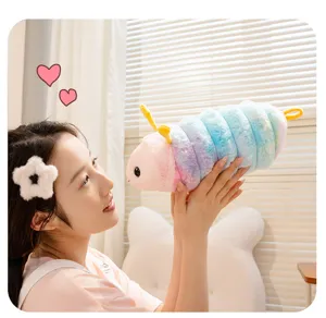Detailed view of a cute colorful caterpillar plush toy held by a smiling model indoors.