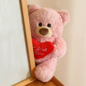 Primo piano di un simpatico orsacchiotto di peluche rosa con cuscino a cuore rosso.