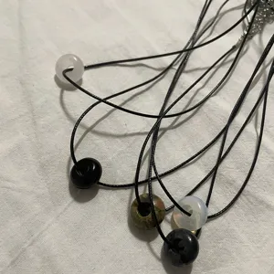 Detailopname van retro edelsteen donut hanger halskettingen met zwart koordje.
