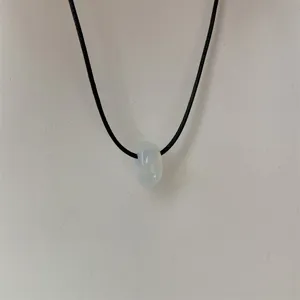 Minimalistische opalen hanger ketting met zwart koord detail, elegant en veelzijdig sieraad.