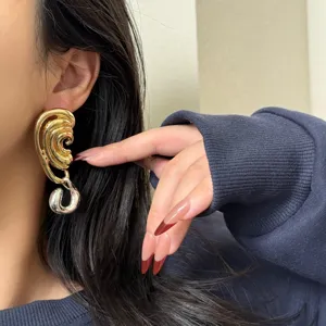 Close-up detail shot of unique two-tone asymmetric statement earrings, highlighting bold metal texture.