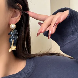 Close-up detail of abstract artistic face drop earring with pearl stud, elegant jewelry.