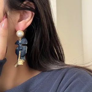 Close-up detail of the abstract human face geometric asymmetric dangle earrings with pearl.