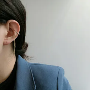 Detaillierte Nahaufnahme einer eleganten goldenen Ohrmanschette mit feiner doppelter Kette.