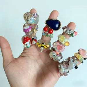 Vue detaillee de bagues emplees en resine coloree et perles, aux motifs faits a la main.