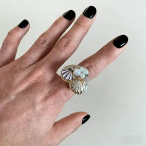 Vue détaillée d'une bague originale en coquillage et perle portée, artisanat d'art unique.