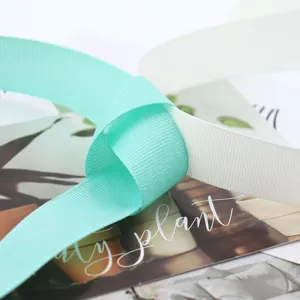 Close-up of turquoise and white glitter grosgrain ribbon tied in a knot for DIY crafts.