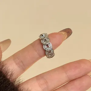 Close-up detailopname van een zilverkleurige ring in oude muntvorm met fonkelende zirkonia's.