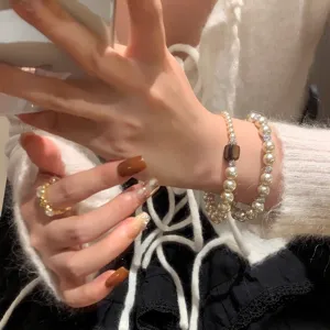 Gros plan détaillé de magnifiques bracelets de perles superposés et bague étincelante.