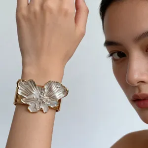 Detail shot of wide gold cuff bracelet featuring pearl shell flower design and elegant style.