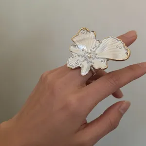 Detailed close-up of statement flower pearl glazed ring wearing on finger chic style
