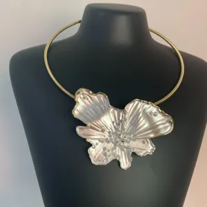 Close-up detail of the pearl-like iridescent flower pendant and sleek golden choker necklace.