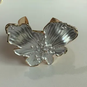 Close-up detail of luxury pearlized drop glaze flower jewelry cuff ring with gold trim.