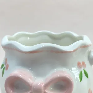 Vue détaillée de la jolie tasse en céramique avec nœud rose façonné et cerises.