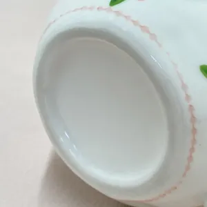 Détail de tasse à café en céramique, bordure perlée rose mignonne et accent de feuille verte.