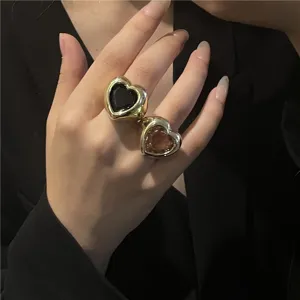 Gros plan de bague cœur en or chunky avec pierre précieuse noire et rose, bijoux tendance.