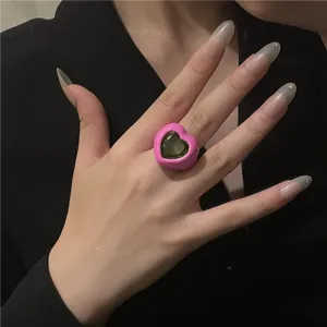 Vue détaillée d'une bague tendance en émail rose avec une grande pierre précieuse verte.