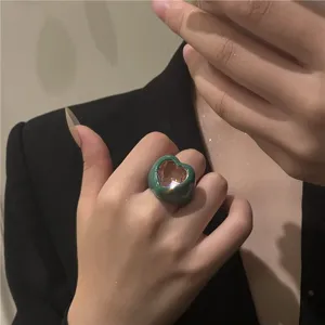 Bague statement cœur chunky avec émail vert et pierre rose, détail bijou mode tendance.