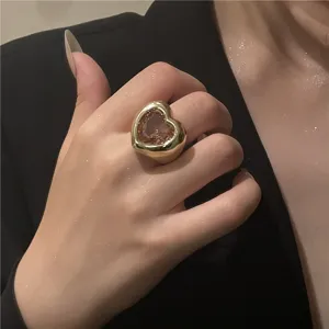 Gros plan détaillé d'une bague dorée audacieuse avec une pierre précieuse en cœur rose.