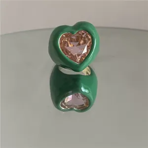 Bague cœur en émail vert chunky avec gros bijou rose étincelant vue de détail gros plan mode.