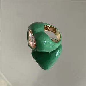 Gros plan bague émail vert épais avec grande pierre rose brillante et finition intérieure dorée.