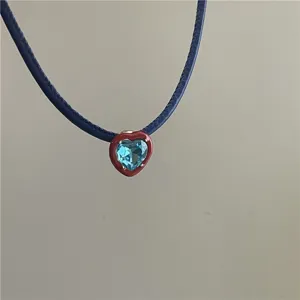 Detailed shot of a stylish blue leather choker necklace featuring a red and blue heart pendant.
