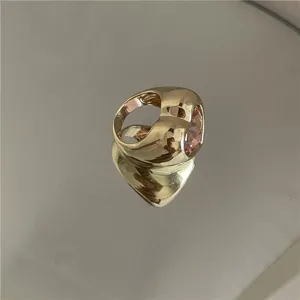 Vue rapprochée d'une bague dorée épaisse avec un grand cristal rose sur surface réfléchissante.