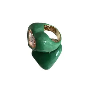 Bague statement épaisse en émail vert avec grand cristal rose et intérieur doré élégant.