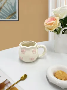 Jolie tasse à café en céramique avec nœuds roses et anse torsadée pour un goûter adorable.