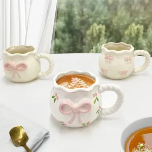 Jolie tasse à café en céramique avec nœud 3D rose et anse tressée, idéale pour le thé.