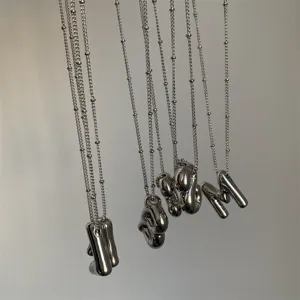 Gedetailleerd overzicht van hippe zilverkleurige letter hanger kettingen met gelaagde kettingen.
