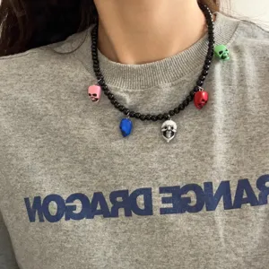 Gedetailleerde close-up van een stijlvolle kraal schedel ketting gedragen op een grijze trui.